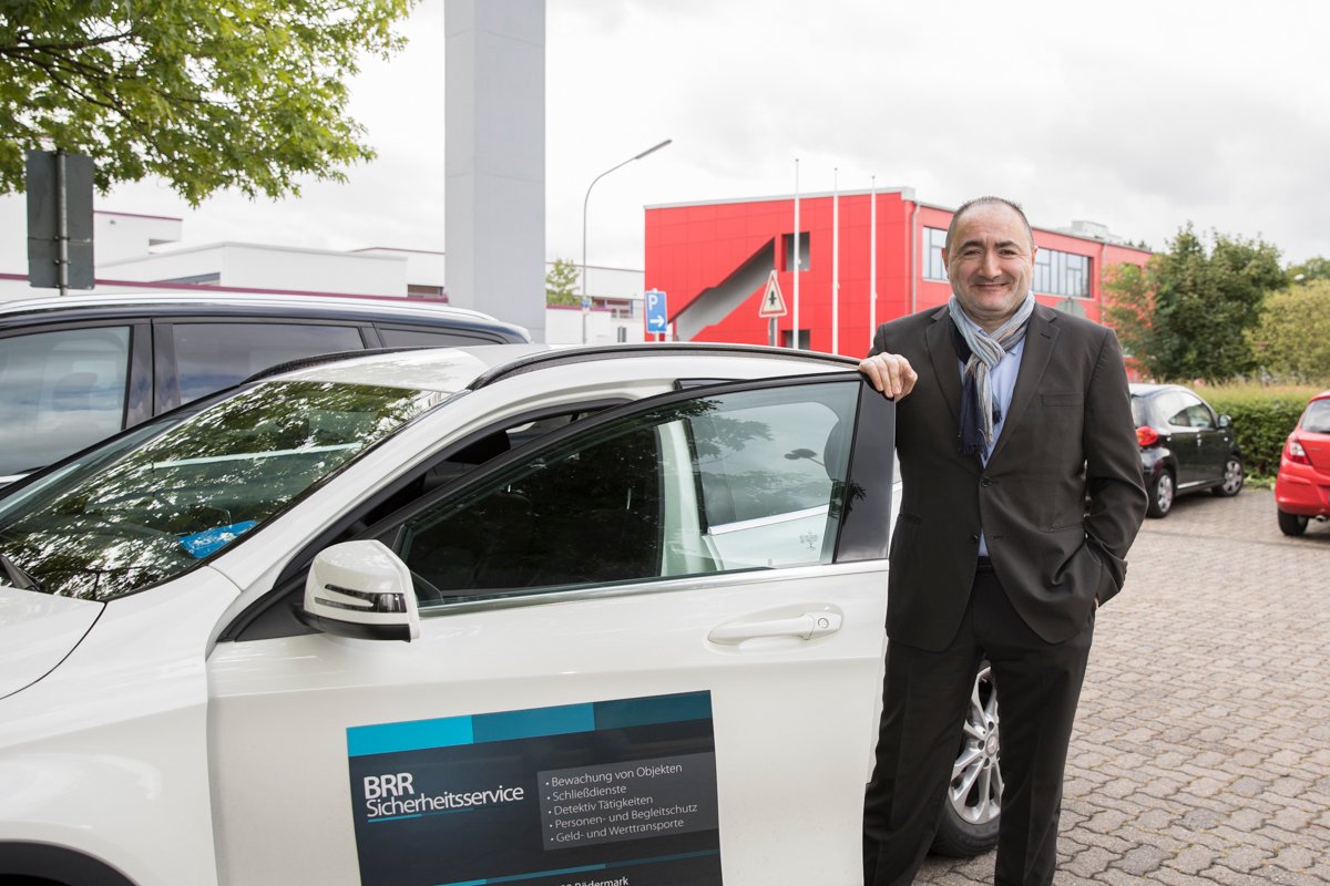 Mustafa Basak-Richter neben einem Fahrzeug von BRR Sicherheitsservice